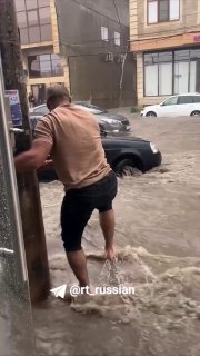 Мужчина отодвинул машину из потока в затопленном Дагестане