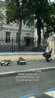 Мужчина на моноколесе везет собаку в кресле на колесиках