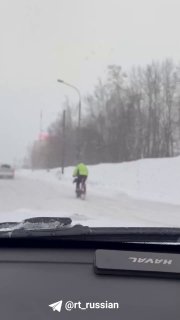 Велосипедист едет по Дмитровскому шоссе в снегопад